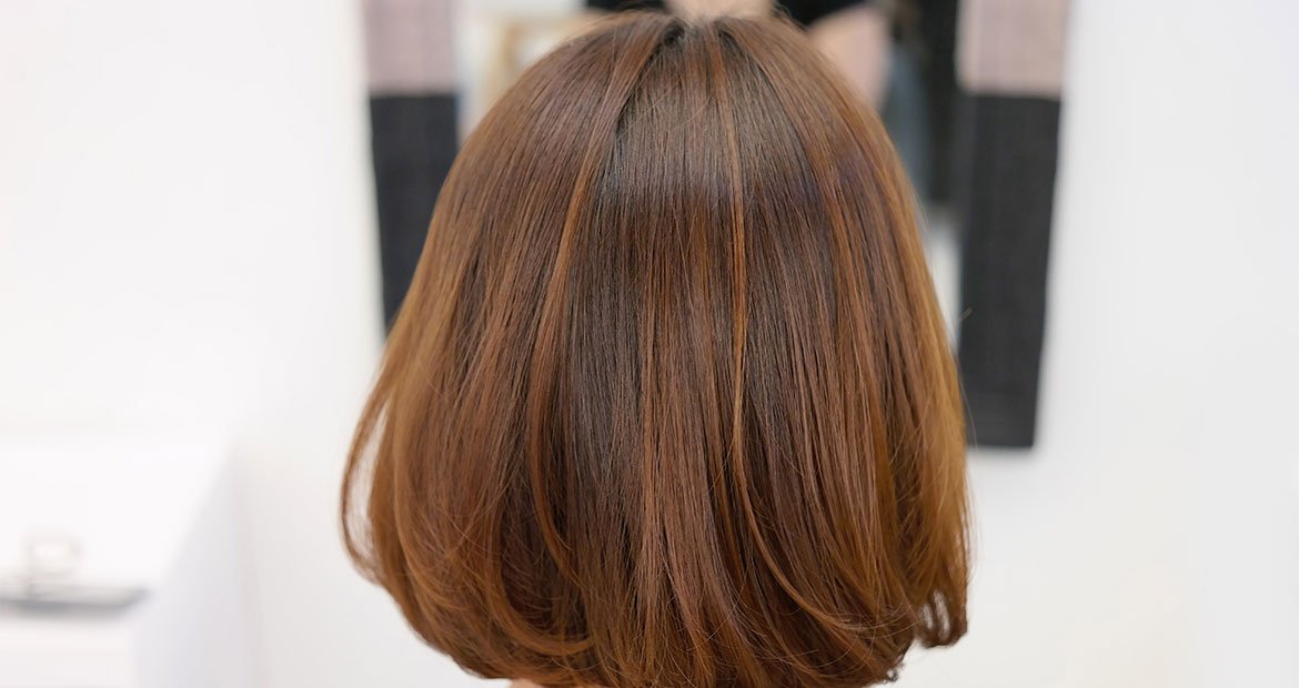 Vista do cabelo curto e liso na altura dos ombros de uma morena iluminada